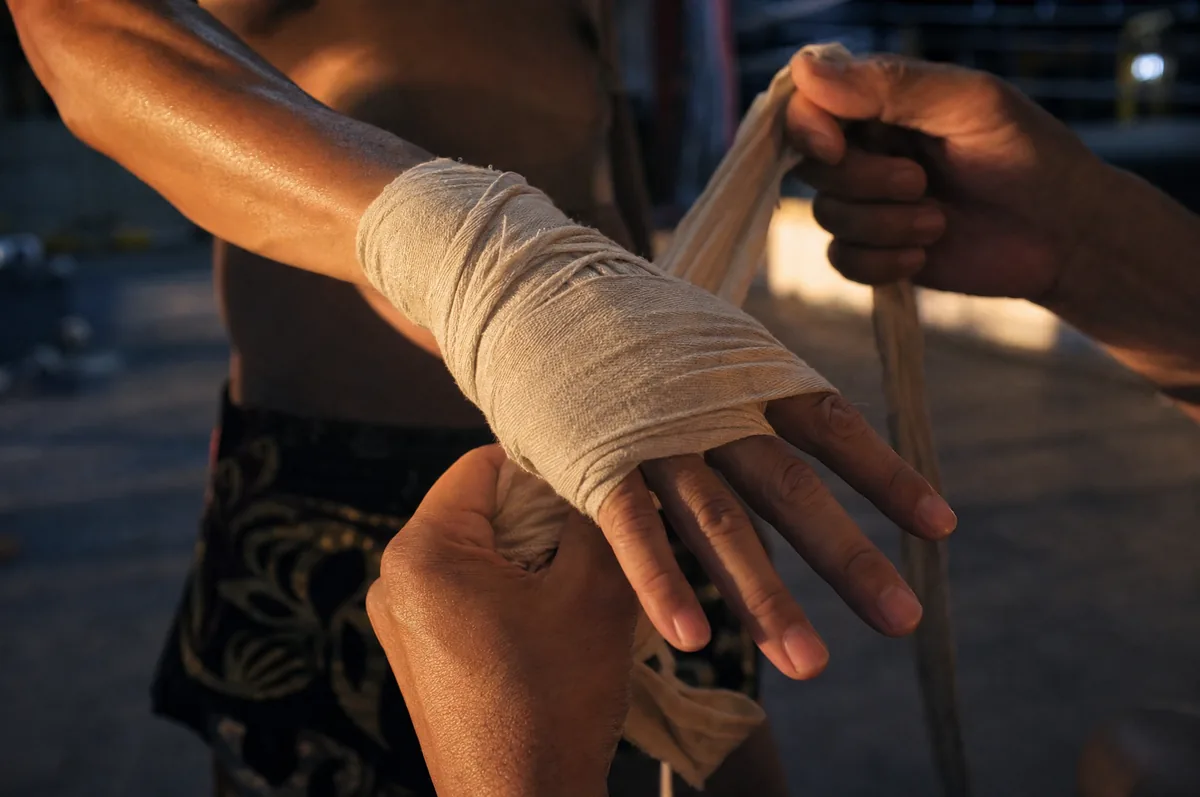 Hands being wrapped in cotton Muay Thai hand wraps in warm evening light