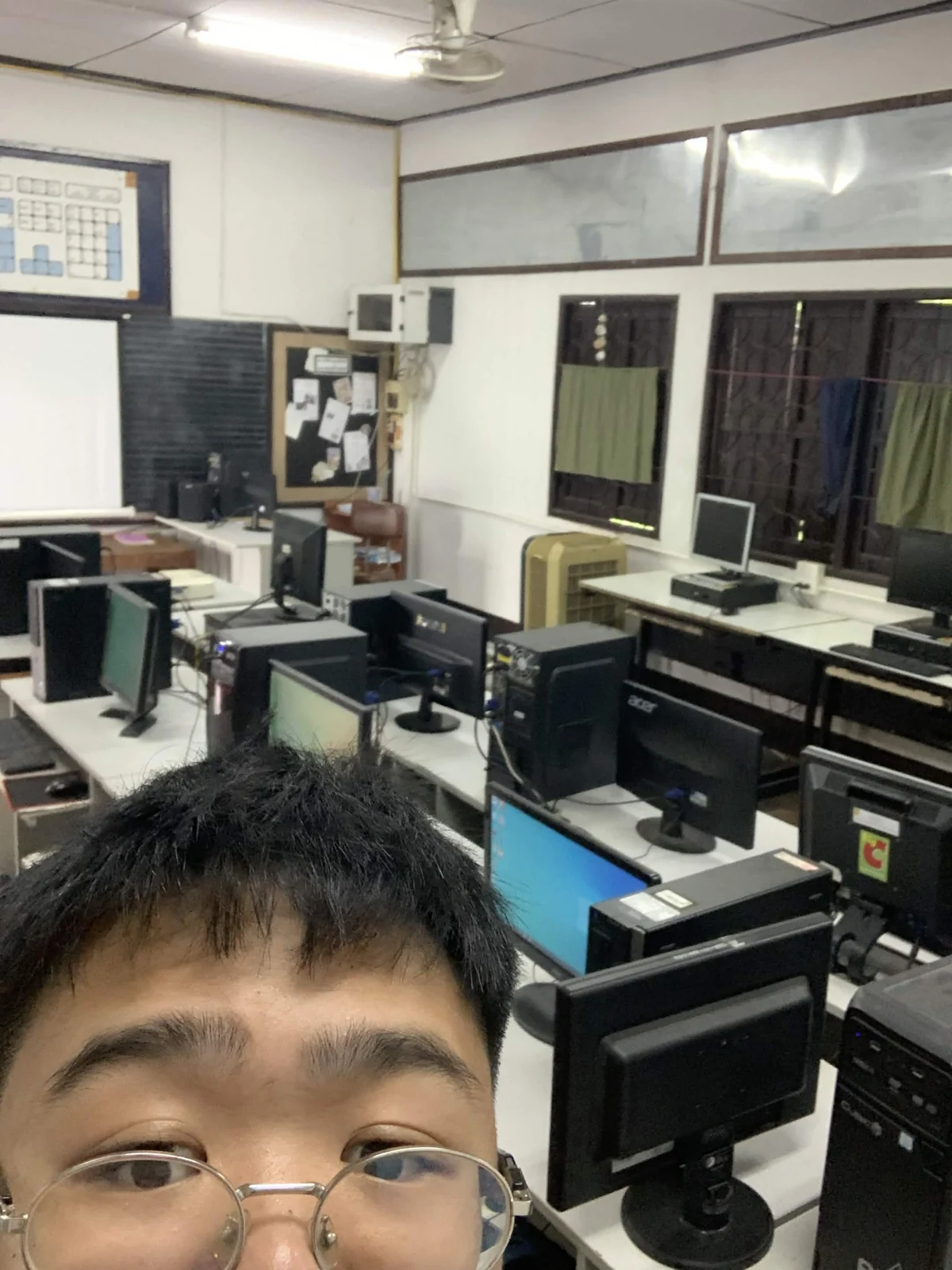 Older desktop computers and monitors arranged in the Ban Ton Ngio School computer lab during setup work.